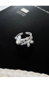 Detailed close-up of a silver flower ring with white pearl on a black book