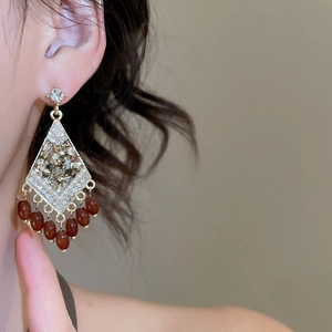Detail shot of vintage rhinestone rhombus earrings with deep reddish brown tassel beads