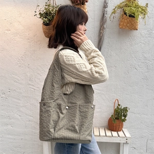 Detail of checkered canvas tote bag featuring three front pockets with silver snap buttons