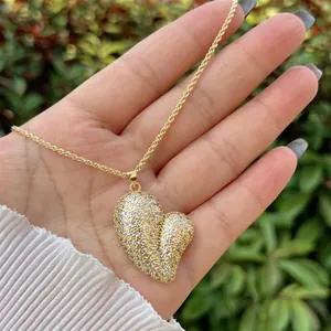 18K gold plated heart pendant necklace with shimmering crystals held by hand outdoors