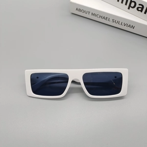Detail view of white square sunglasses with dark lenses on a minimalist grey surface