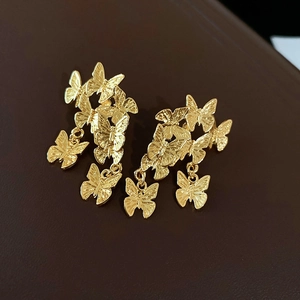 Vue détaillée de boucles d'oreilles papillon dorées avec métal texturé et pendentifs