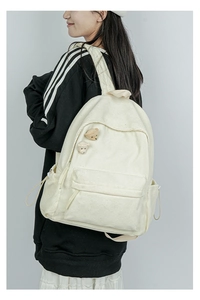 Detailansicht eines cremefarbenen Cord-Rucksacks mit süßen Bären-Accessoires am Model