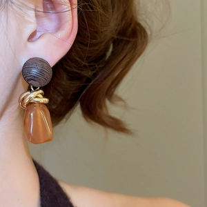 Gros plan de boucles d'oreilles géométriques avec bois, anneaux d'or et résine ambre