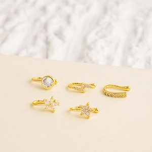 Detail view of five golden non-piercing ear clips with zircon stars and lightning shapes