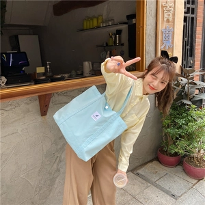 Detail of light blue canvas tote bag with magnetic snap closure and side label