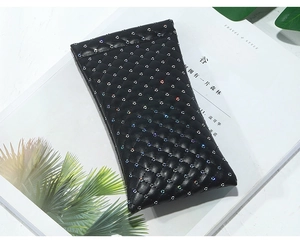 Detailed view of quilted black leather pouch with colorful rhinestones on a magazine