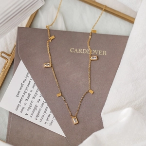 Elegant gold fringe necklace with square crystals on vintage paper background