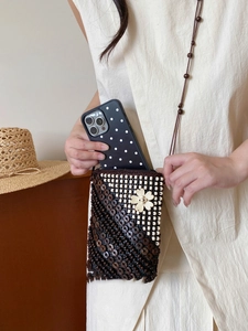 Detail of bohemian handmade woven coconut shell bag showing phone capacity and floral design