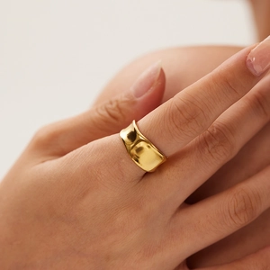Detailed view of wide 18K gold plated ring with irregular wave texture and hammered finish