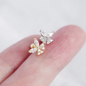 Macro shot of silver and gold butterfly stud earrings with sparkling zircon inlay