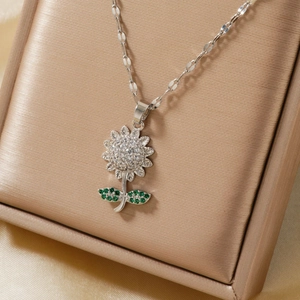 Macro detail of sunflower pendant with white and green zircons on champagne satin