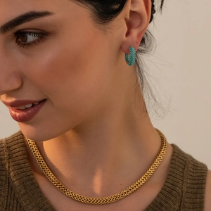 Close-up of a model wearing gold herringbone chain and turquoise bead hoop earrings