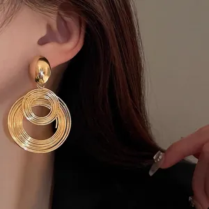 Retro gold layered hoop earrings with a metallic mirror finish on a female model
