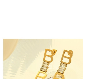 Vue détaillée des boucles d'oreilles dorées en forme de B avec cristal transparent