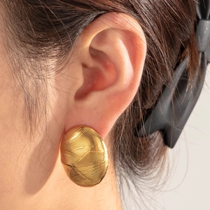 Golden geometric earrings with woven texture worn by model for elegant style look
