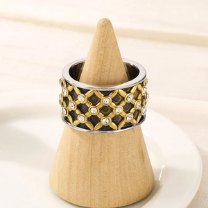 Détail macro d'une bague large dorée avec diamants sur un support en bois naturel
