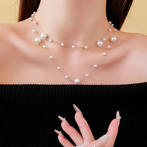Detail view of a double-layered gold necklace with pearls worn on a model neck