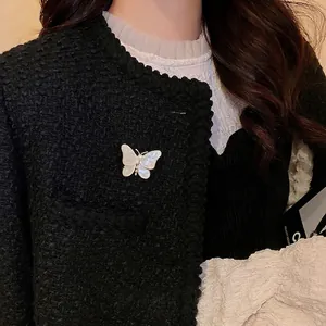 Élégante broche papillon plaquée or avec ailes en nacre et perles sur veste en tweed