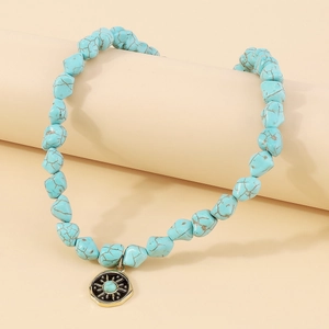 Detail of bohemian turquoise beaded necklace with sun pattern gold pendant on prop