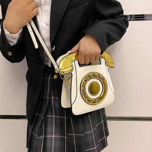 Creative white telephone shaped crossbody bag with gold dial and metallic handle detail