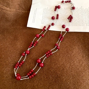Detailed view of layered vintage long necklace with vibrant red beads and silver chains