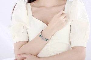 Detailed view of silver twisted cable cuff bracelet with blue and clear stone finials