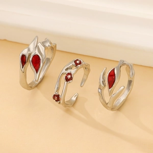 Macro detail of three-piece silver punk rings featuring leaf motifs and red gemstones