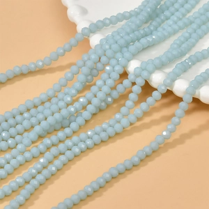 Macro shot of 4mm light blue faceted rondelle glass beads on a vintage white plate