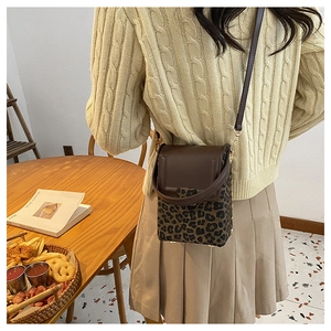 Detail of a mini crossbody bucket bag featuring brown leather and leopard print