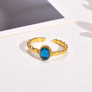 Detailed view of a gold twist band ring featuring an oval blue gemstone inlay