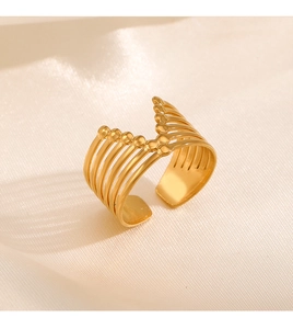 Macro shot of gold wide open ring featuring parallel lines and delicate bead accents