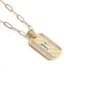 Gros plan du pendentif doré avec lettre P, texture tissée et cristaux sur chaîne trombone