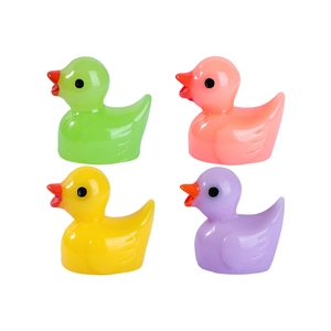 Set of four colorful resin duck figurines in yellow pink green and purple on white backdrop