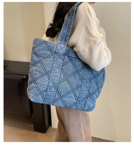 Détail du grand sac cabas en jean matelassé porté par un mannequin pour montrer la taille