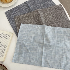 Detail of cotton linen placemats with stripes and grid patterns in a cozy home setting
