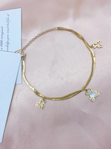 Detail eines goldfarbenen doppellagigen Armbands mit Bärenanhängern auf rosa Satinhintergrund