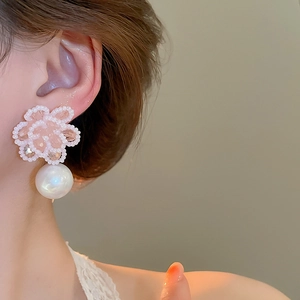 Close-up of elegant flower bead earrings with pink petals and a large white hanging pearl