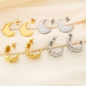 Détail de boucles d'oreilles en U dorées et argentées, textures lisses et tressées sur soie
