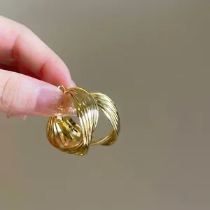 Macro view of multi-layered gold circle hoop earrings held to show scale and texture