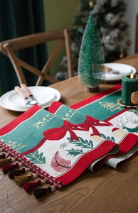 Detail of Christmas table runner with embroidered bow and tassel on a festive table