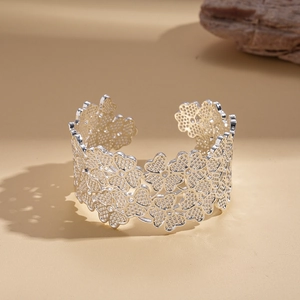 Detailed view of silver open cuff bracelet featuring intricate cutout flower patterns