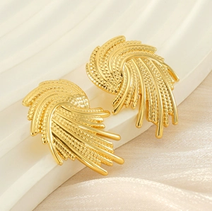 Macro detail of gold-tone geometric spiral earrings with radiant textured finish