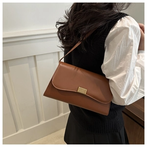 Detailed view of brown leather crossbody bag with elegant gold buckle on a model