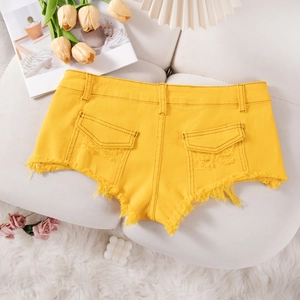 Pantaloncini di jeans gialli con bordi sfrangiati e tasche posteriori su tappeto morbido