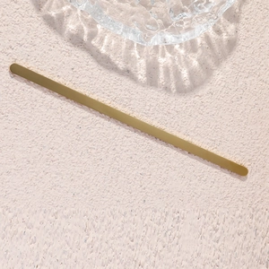 Detailed view of a minimalist gold C-shaped stainless steel bracelet on a textured background