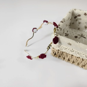 Detail of red velvet roses, white pearls and golden leaves on a metal wavy headband