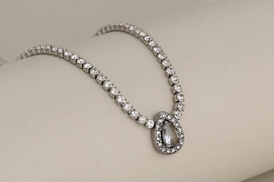 Macro shot of silver-tone stainless steel chain with sparkling teardrop crystal pendant