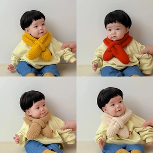 Detail of soft knitted baby scarves in yellow, red, and camel with cross-over design