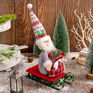 Christmas gnome doll with grey coat and striped hat sitting on a red sleigh ornament